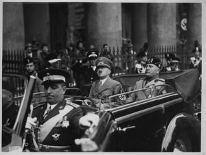 Adolf Hitler und Benito Mussolini fahren 1938 in einem offenen Auto durch Rom, umgeben von Soldaten und Zuschauern. Historisches Schwarz-Weiß-Foto aus der Zeit des Nationalsozialismus und des Faschismus